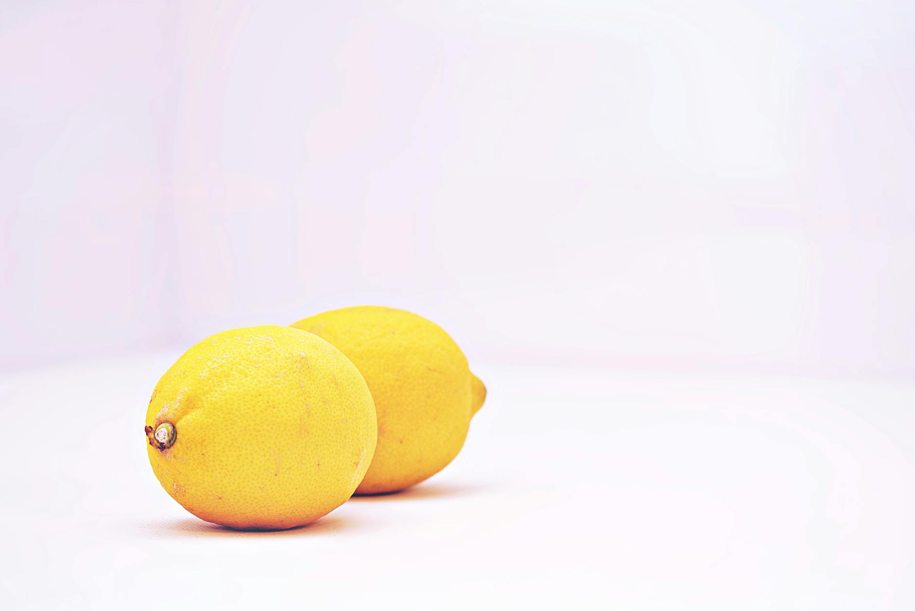 Two fresh lemons against a white background, symbolizing gentle restoration and natural pleasure