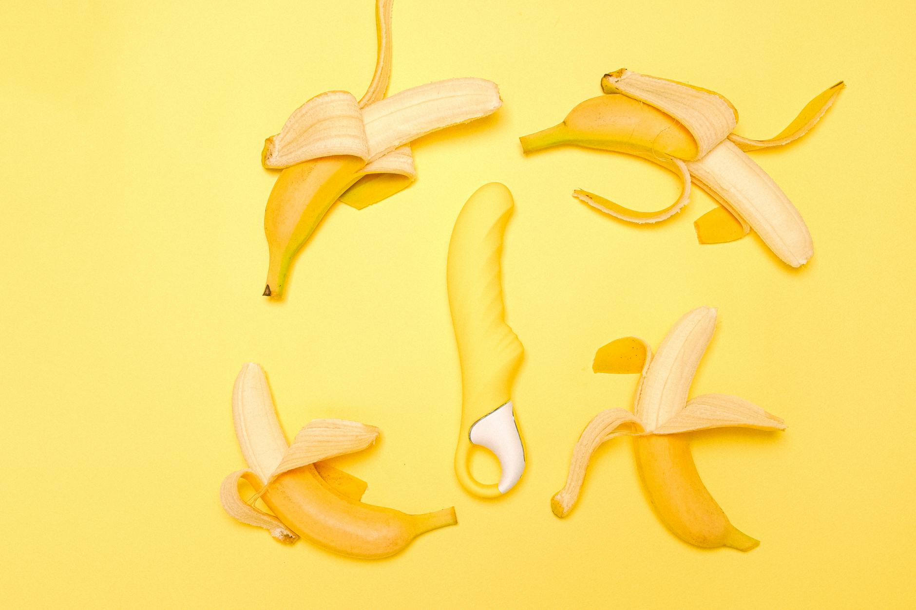 Yellow silicone vibrator surrounded by bananas on a yellow background, symbolizing reconnection to pleasure and sensation