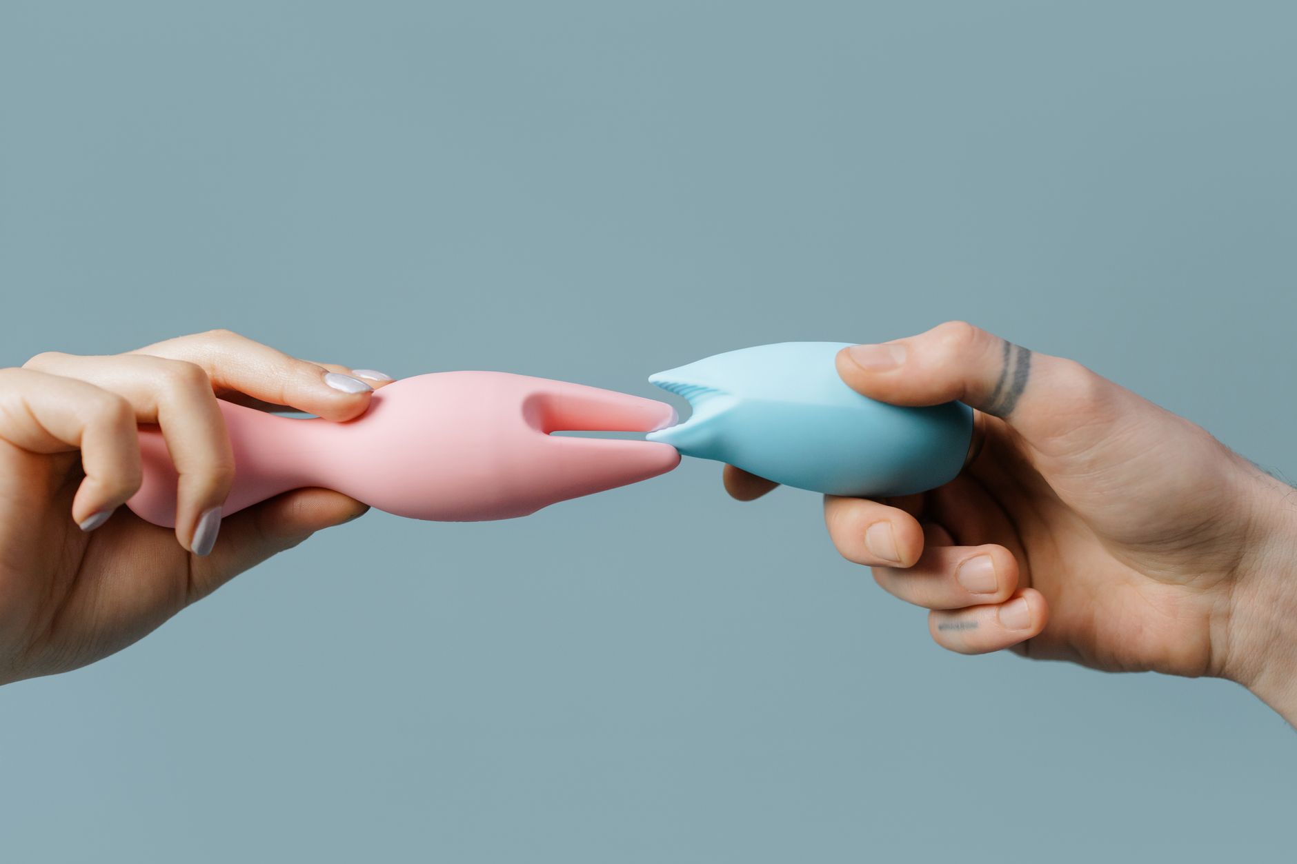 Close-up of a hand holding an orange vibrator against a minimalistic purple backdrop, showcasing modern sensuality