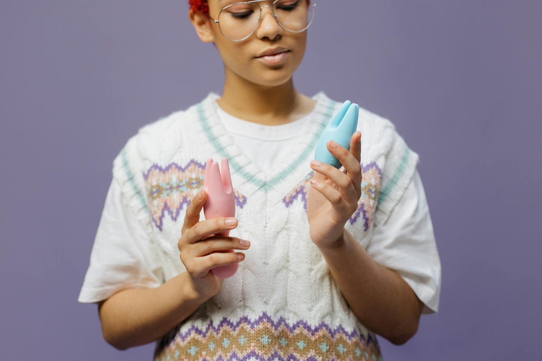 Woman in thoughtful pose holding modern clitoral vibrators, symbolizing intentional pleasure and self-discovery.