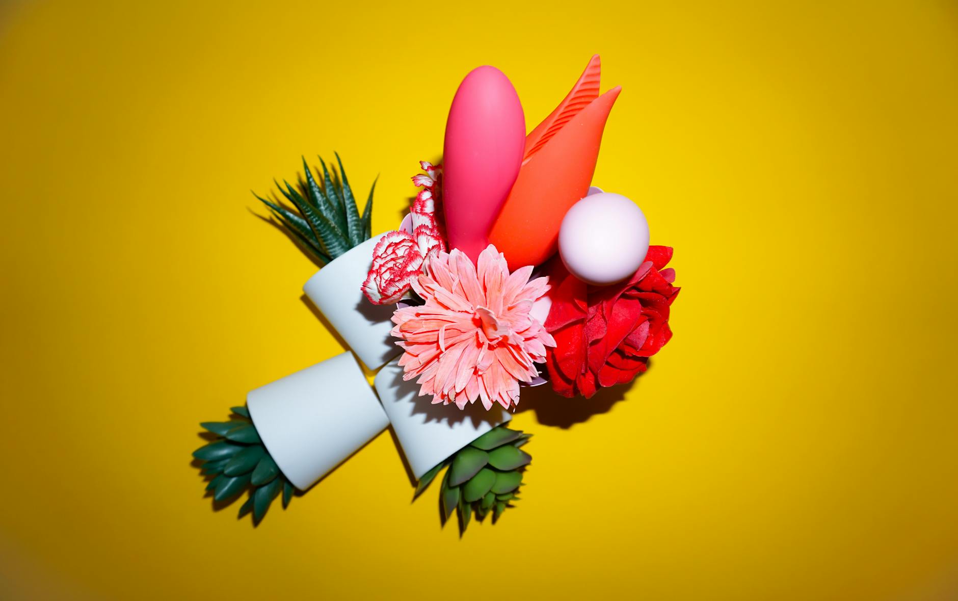 A hand reaching over a variety of colorful clitoral vibrators arranged on a table.
