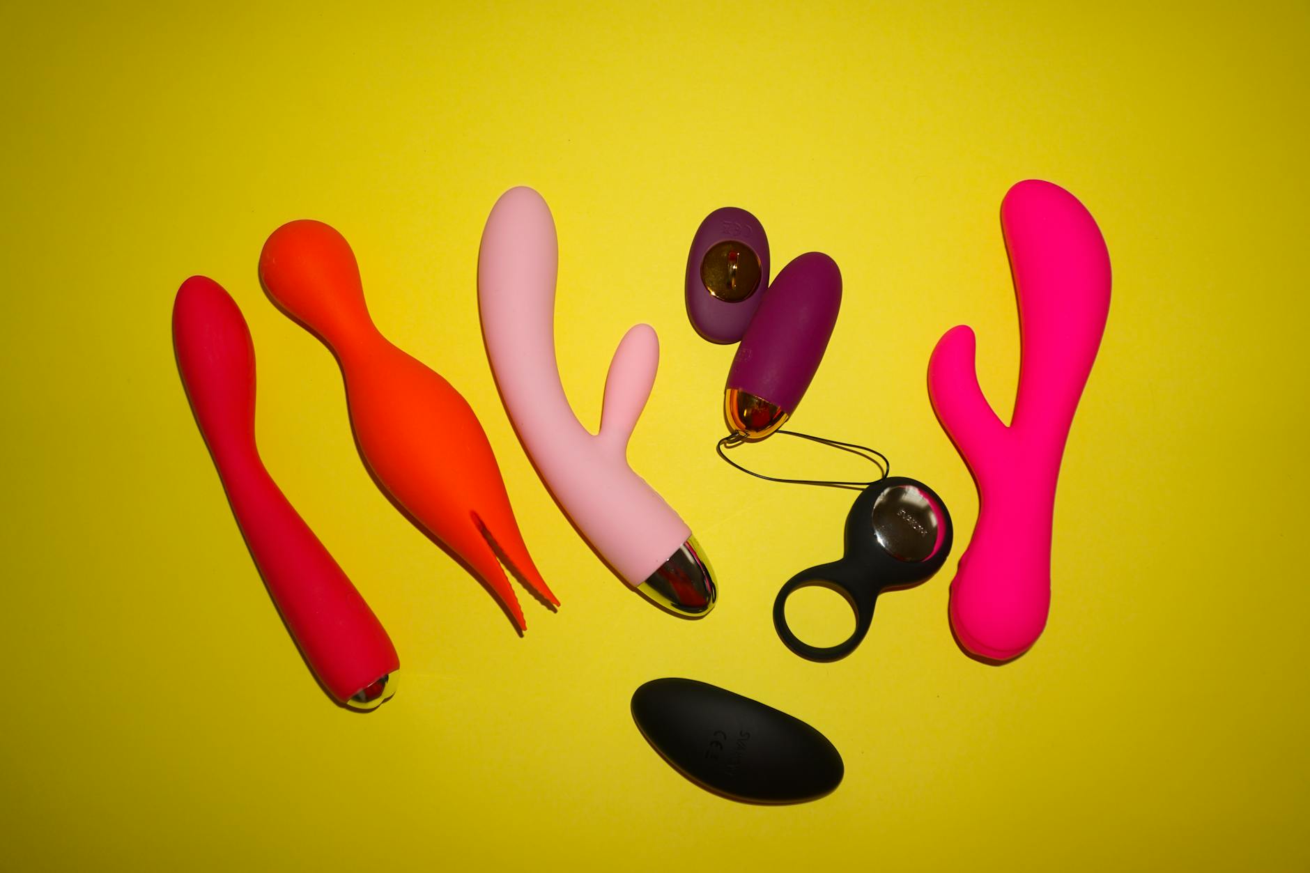 Woman holding a pink vibrator with art books in background, emphasizing personal pleasure and autonomy